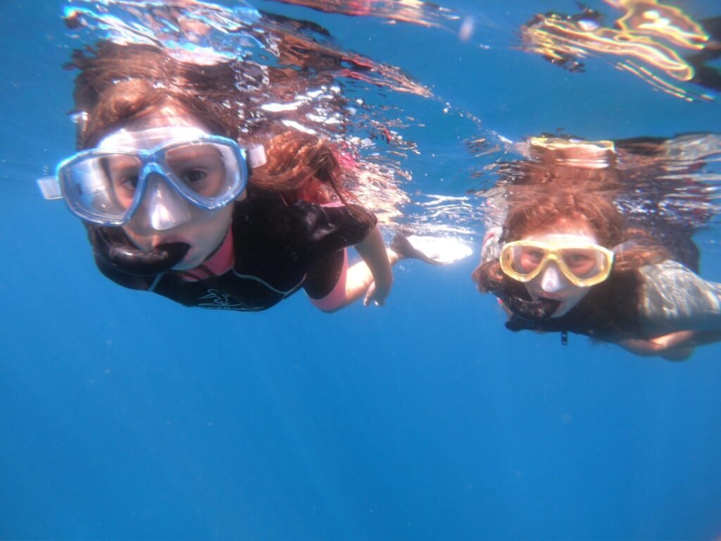 Two people snorkeling underwater with masks, enjoying a guided snorkeling experience